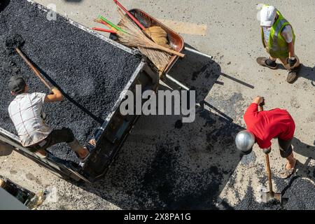 Ein Arbeiter lädt zerquetschten Asphalt auf das Bett eines Lastwagens Stockfoto
