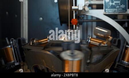 Automatisierte Maschine mit rotierenden Spulen und Draht. Kreativ. Spulen drehen sich auf dem Stapel mit Wickeldraht. Industriemaschine dreht und wickelt Kupferdraht auf Stockfoto