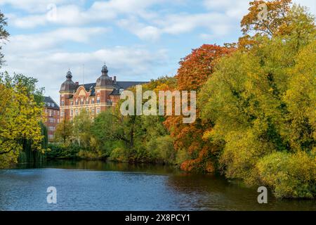 Tauchen Sie ein in die herbstliche Eleganz mit diesem Bild eines Herrenhauses am See, umgeben von lebhaftem Herbstlaub Stockfoto