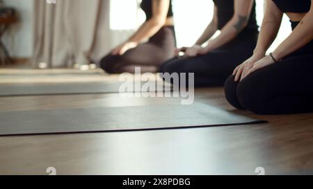 Drei hübsche, schlanke Frauen, die Yogamatten ausbreiten, bevor sie im Studio trainieren. Medien. Mädchen mit Gruppentraining. Stockfoto