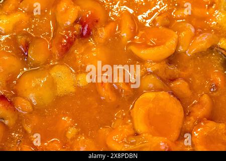 Aprikosenmarmelade in einer Schüssel gekocht und mit einem Holzlöffel gestaut Stockfoto