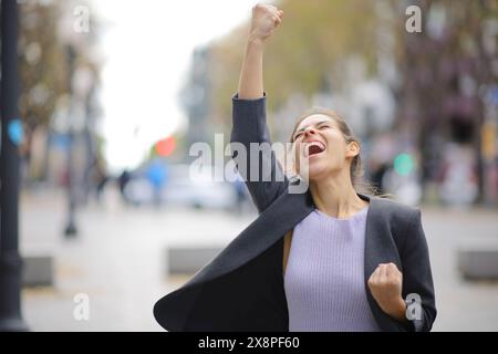 Aufgeregter Manager, der Erfolg feiert und die Arme auf der Straße hebt Stockfoto