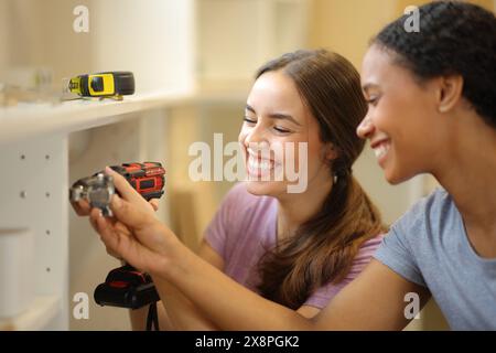 Schwarz-weiße Frauen, die Küchenmöbel in einem Haus zusammenbauen, das gerade reformiert wird Stockfoto