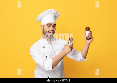 Professioneller Koch mit Shaker auf gelbem Hintergrund Stockfoto