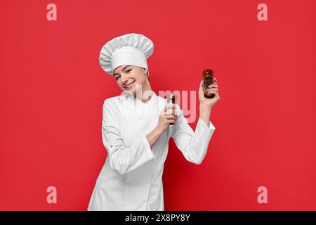 Professioneller Koch mit Salz- und Pfefferstreuer auf rotem Hintergrund Stockfoto