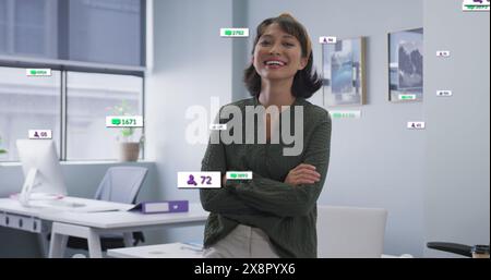 Bild von Social-Media-Ikonen über asiatische Frau mit gekreuzten Armen, die im Büro lächelt Stockfoto