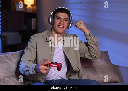 Emotionaler Mann, der Videospiele mit dem Controller zu Hause spielt Stockfoto