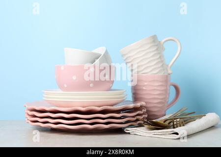 Wunderschönes Keramikgeschirr, Tassen und Besteck auf hellgrauem Tisch Stockfoto