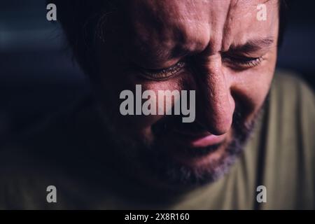 Mann weint in dunklem Raum, Traurigkeit und Trauer Konzept, dezent mit selektivem Fokus Stockfoto