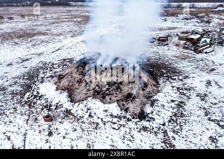 Brennender Dunghaufen auf dem Bauernhof, Luftverschmutzung und Verschmutzung, Luftaufnahme von Drohnen-pov, Hochwinkelansicht Stockfoto