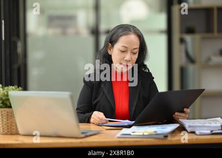 Professionelle leitende Buchhaltungsmanagerin, die Finanzdokumente am Arbeitsplatz überprüft Stockfoto