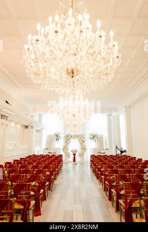 Luxuriöse Hochzeitszeremonie mit roten und goldenen Stühlen und Blumenbogen Stockfoto