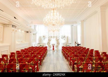 Hochzeitszeremonie mit roten Stühlen, weißen Blumen und Kronleuchtern Stockfoto