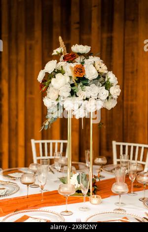 Hoher Hochzeitstisch mit weißen und orangen Blumen Stockfoto