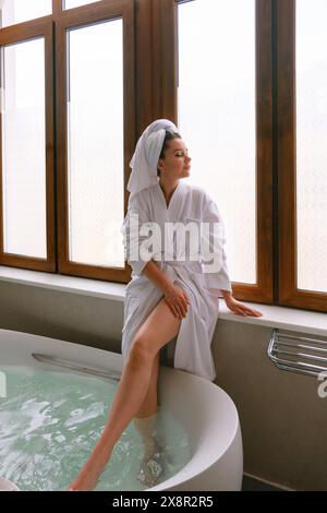 Eine schöne Frau sitzt auf der Fensterbank im Hotelbad. Stockfoto