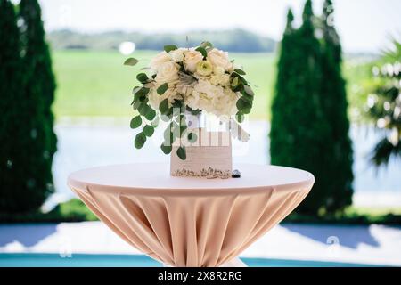 Elegante Blumenarrangements und Hochzeitseinladungen am Seeufer Stockfoto