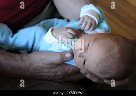 Nahaufnahme eines Großvaters, der ein Neugeborenes hält, und einen zärtlichen Moment teilt Stockfoto