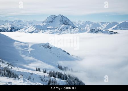 Schneebedeckte Berge unter klarem Himmel mit nebeligen Tälern Stockfoto