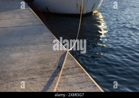 Das Boot ist mit einem Seil verbunden und wirft einen Schatten auf den Pier Stockfoto