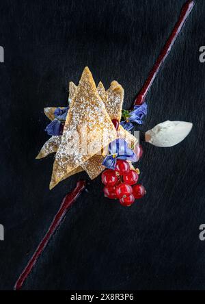 Kunstvoll überzogenes Dessert mit essbaren Blumen und Obstgarnitur Stockfoto