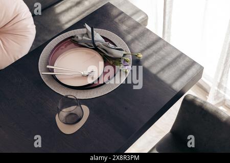 Elegante Tischeinrichtung mit Tellern und Blume auf einem schwarzen Tisch Stockfoto