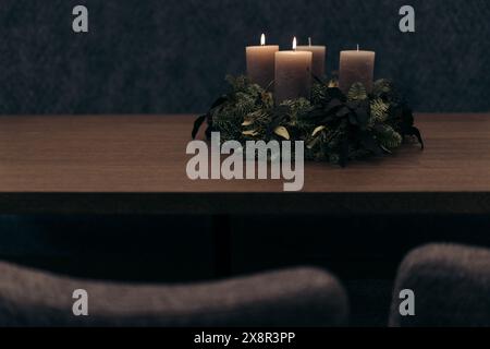 Zündete Kerzen auf einem Kranz-Herzstück auf einem Holztisch an Stockfoto