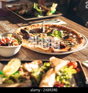 Sonnendurchflutete Pizza mit frischen Meeresfrüchten auf einem rustikalen Holztisch Stockfoto