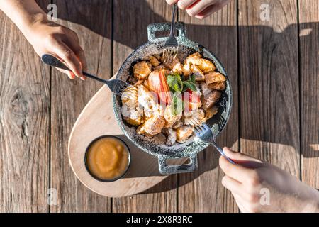 Genießen Sie einen traditionellen österreichischen Kaiserschmarren auf einem sonnigen Holztisch Stockfoto