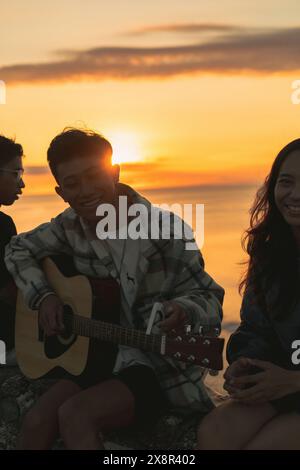 Ein paar balinesische Teenager, die bei Sonnenuntergang verliebt sind, spielt Guy Gitarre. Stockfoto