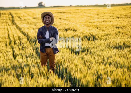 Afrikanischer Bauer steht auf seinem wachsenden Weizenfeld. Er ist zufrieden mit dem Fortschritt der Pflanzen. Stockfoto