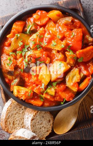 Gemüse-Gyuvech Auberginen, Paprika, Tomaten, Zwiebeln, Karotten, frisches Grün auf der Schüssel auf dem Tisch. Vertikale Draufsicht von oben Stockfoto