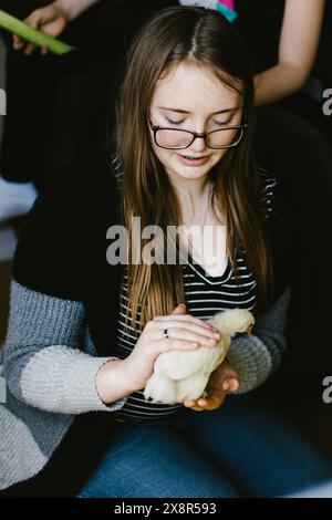 Das Teenager-Mädchen hält das gelbe Baby liebevoll in den Händen Stockfoto