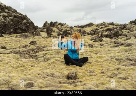 Eine Reisende Frau macht ein Foto auf ihrem Handy in Island. Stockfoto