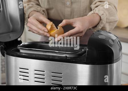 Teig herstellen. Frau, die Ei in die Brotbackpfanne bricht, Nahaufnahme Stockfoto