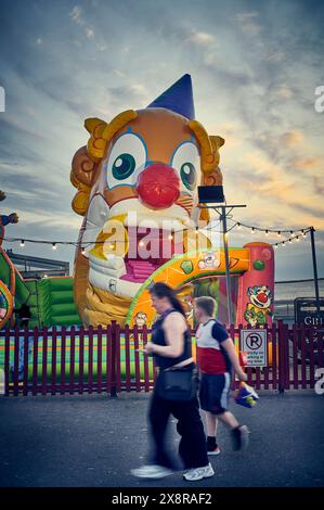 Frau und kleiner Junge, die an einem Hüpfschloss an der Blackpool Promenade vorbeilaufen Stockfoto