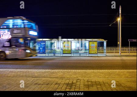 Der Bus fährt spät in der Nacht in Blackpool an einer Straßenbahnhaltestelle vorbei Stockfoto