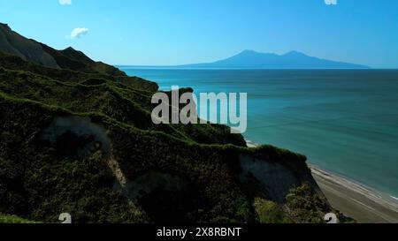 Felsen einer unbewohnten Insel im Mittelmeer. Clip. Bewaldete grüne Hügel und blaues Meer mit wolkenlosem Horizont im Hintergrund. Stockfoto