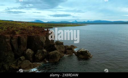 Blick aus der Vogelperspektive auf das ruhige Meer und die Steinklippen an der Küste von Oregon. Clip. Luftlinie der Meereswasseroberfläche und grüne Wiesen. Stockfoto