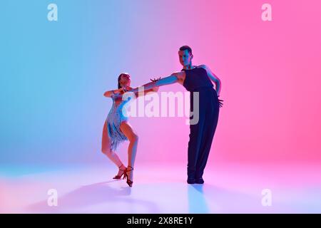 Tänzer im Ballsaal, Mann und Frau in Modekostümen der Bühne posieren in Neonlicht vor verlaufendem Hintergrund. Stockfoto