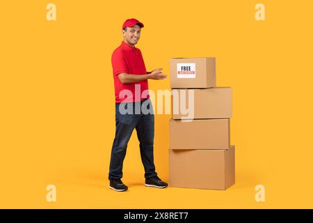 Lächelnder Mitarbeiter in roter Uniform mit Kisten Stockfoto