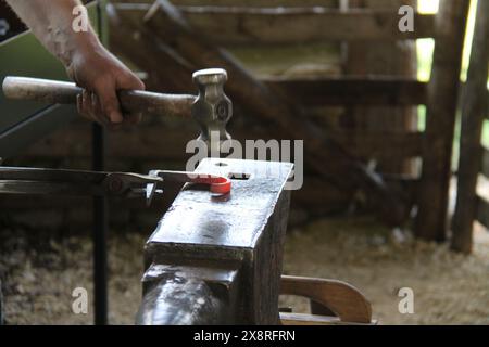 Ein Schmied hämmert Red Hot Metal auf einen Amboss. Stockfoto