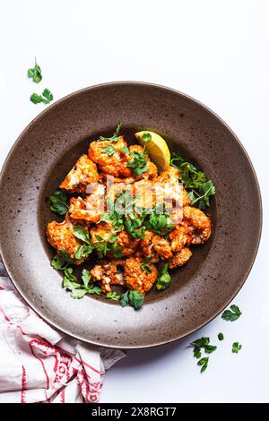 Gebackener Blumenkohl in Tomatensauce mit Kräutern, weißer Hintergrund, Draufsicht. Veganes Rezept. Stockfoto