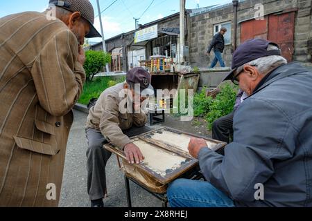 Gyumri, Armenien - 25. Mai 2024: Männer spielen Backgammon auf einer Straße in Gyumri, Armenien. Stockfoto