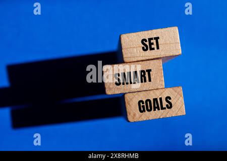 Setzen Sie intelligente Ziele Wörter auf Holzblöcken mit blauem Hintergrund. Symbol für „Intelligente Ziele festlegen“. Kopierbereich. Stockfoto