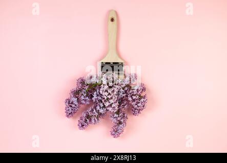 Ansicht von oben auf lila Blumen auf rosafarbenem Hintergrund. Kreative Pinselkomposition. Federtapete, flach, Kopierraum. Stockfoto