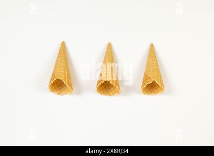 Blick von oben auf drei Eiswaffelkegel auf weißem Hintergrund. Sommertapete, flach, Kopierraum. Stockfoto