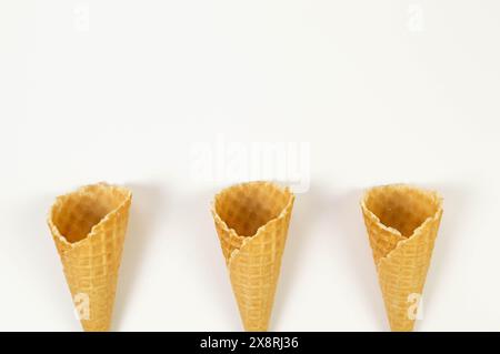 Blick von oben auf drei Eiswaffelkegel auf weißem Hintergrund. Sommertapete, flach, Kopierraum. Stockfoto