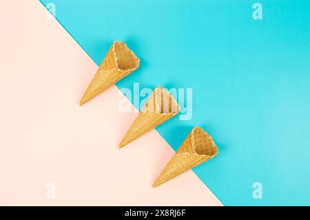 Blick von oben auf drei Eiswaffelkegel auf farbenfrohem Hintergrund. Sommertapete, flach, Kopierraum. Stockfoto