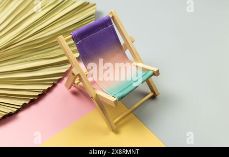 Farbenfroher Strandstuhl, getrocknete Palmblätter auf farbenfrohem Hintergrund. Sommer-, Urlaubs- und Strandkonzept. Kreative Komposition, Kopierbereich. Stockfoto