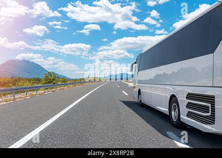 Ein weißer Touristenbus fährt auf einer Bergstraße. Stockfoto